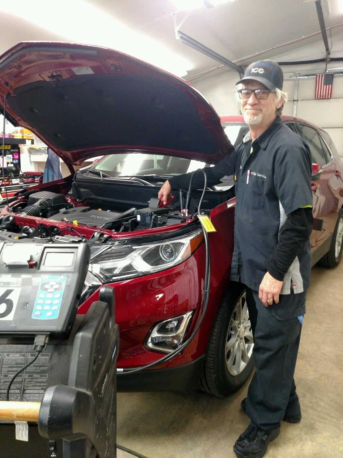 Technician working on a vehicle with hood open